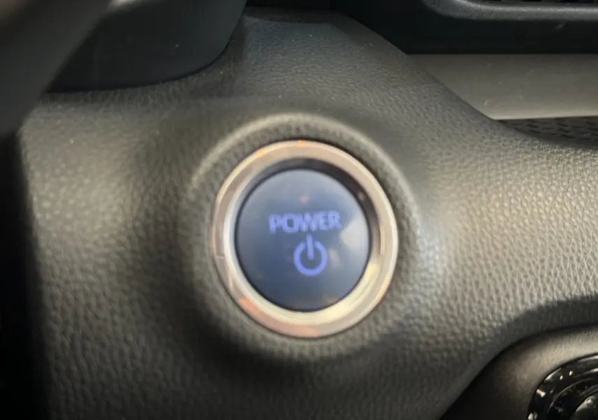 Bouton démarrage Power éclairé en bleu sur tableau de bord noir de la Toyota Yaris hybride 2022.