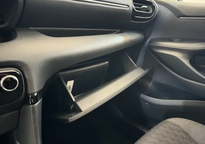 Intérieur côté passager de la Toyota Yaris hybride 2022, boîte à gants ouverte et tableau de bord noir.