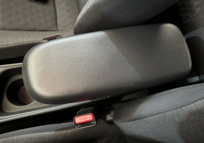 Accoudoir central noir en cuir avec bouton de ceinture rouge, intérieur tissu gris de Toyota Yaris hybride 2022.