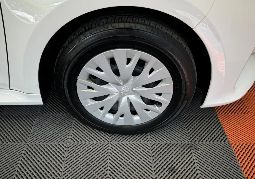 Gros plan sur la roue avant gauche de la Toyota Yaris hybride blanche, mettant en valeur la jante avec enjoliveur d'origine.