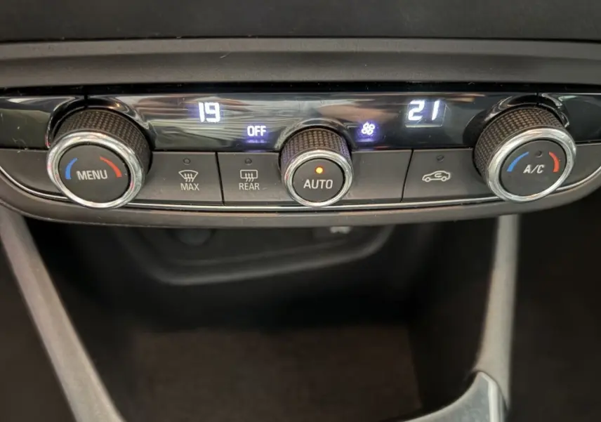 Gros plan sur la commande de climatisation 2 zones de l’Opel Crossland blanc, avec affichage digital et boutons rotatifs.