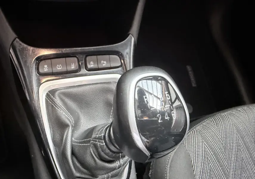 Gros plan sur le levier de vitesses manuel noir et chrome de l’Opel Crossland 1.2 Turbo Elegance, avec boutons de contrôle à proximité.