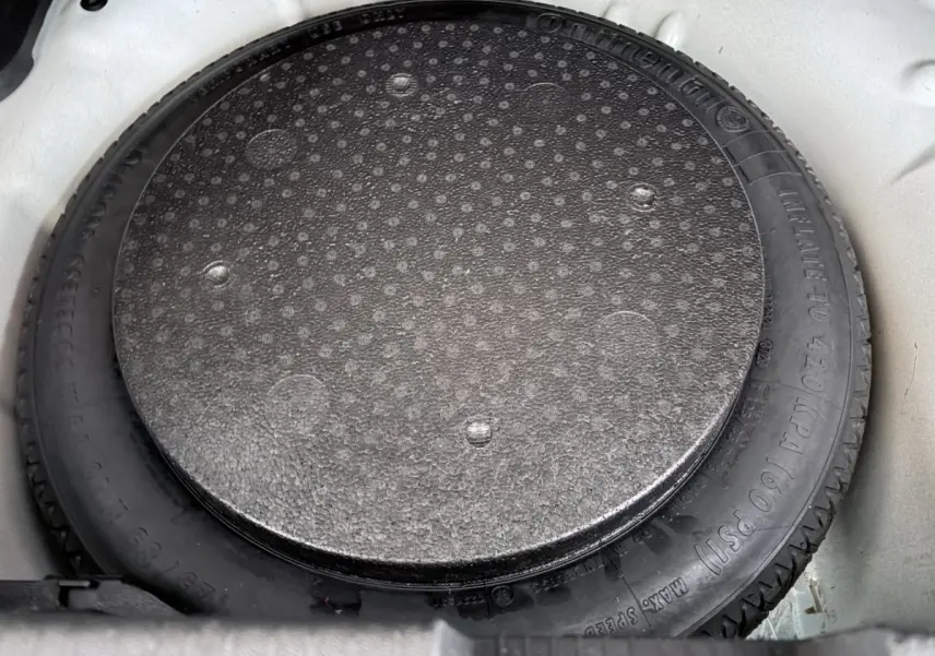 Gros plan sur la roue de secours noire dans le coffre blanc d’un Opel Crossland 2021.