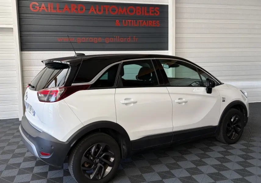 Vue 3/4 arrière droite de l’Opel Crossland blanc avec toit noir et jantes noires dans un garage.