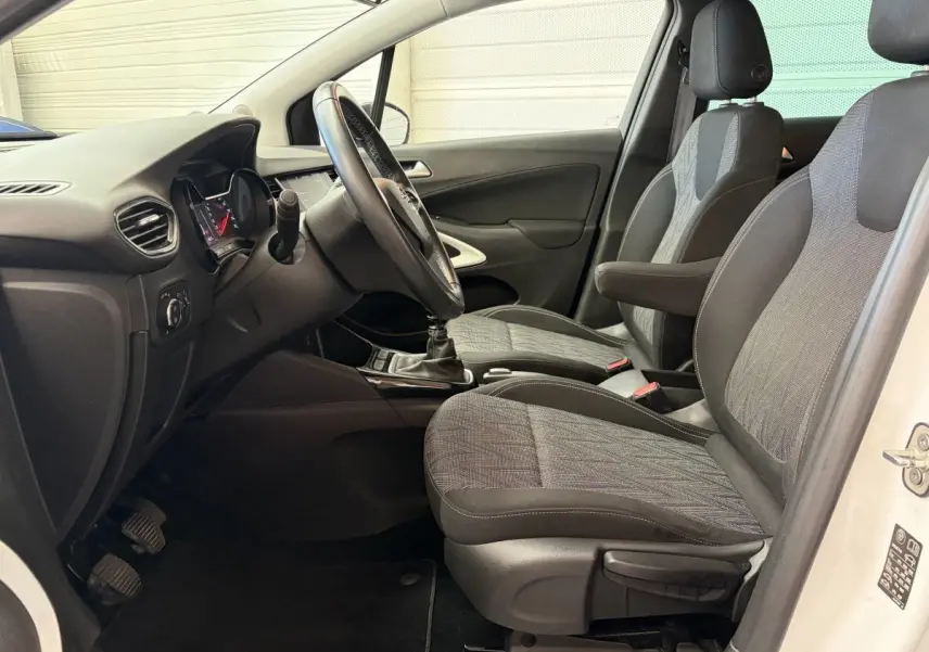 Vue intérieure côté conducteur de l’Opel Crossland blanc, montrant les sièges tissu et le volant multifonctions cuir.