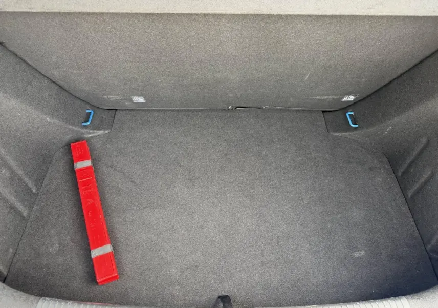 Coffre spacieux de MG3 1.5 Hybrid+ 195ch Luxury, vue intérieure avec tapis gris et triangle de signalisation rouge.