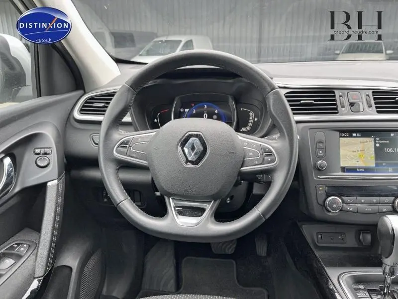 Vue intérieure centrée sur le volant cuir multifonction d’un Renault Kadjar gris platine avec écran tactile et commandes au volant.