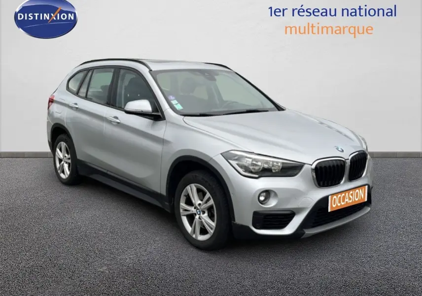 BMW X1 18i gris argent métal en 3/4 avant droit, avec calandre noire et jantes alliage 17 pouces.
