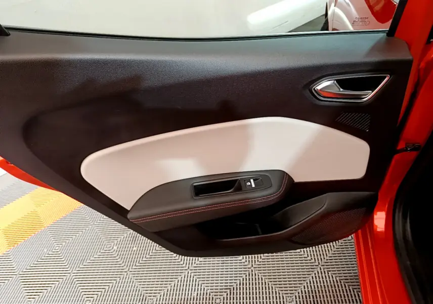 Gros plan sur la porte avant gauche orange de la Renault Clio Initiale Paris 2021 avec habillage noir et beige.