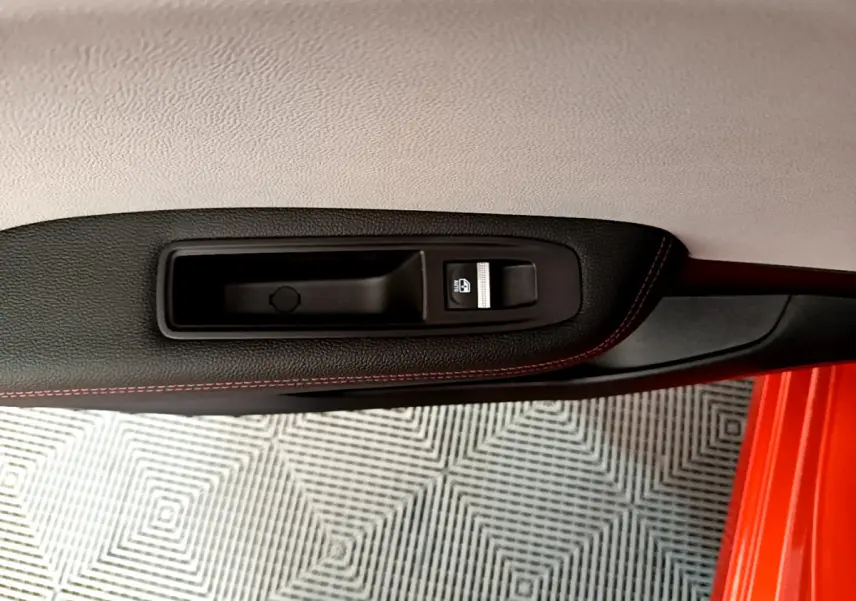 Poignée intérieure côté gauche avec bouton de verrouillage sur porte orange d'une Renault Clio Initiale Paris E-TECH 2021.