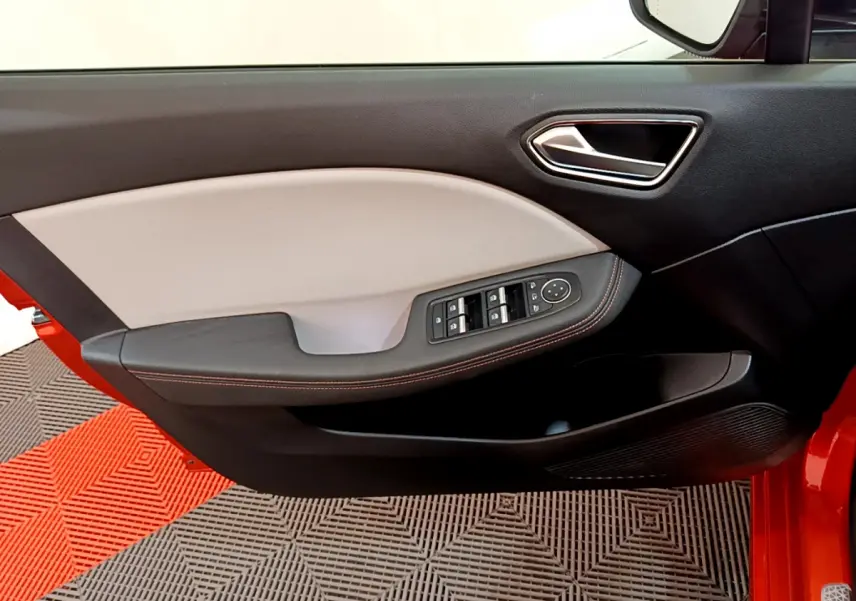 Intérieur côté gauche de la porte d'une Renault Clio orange 2021, avec commandes électriques et garniture bicolore beige et noire.