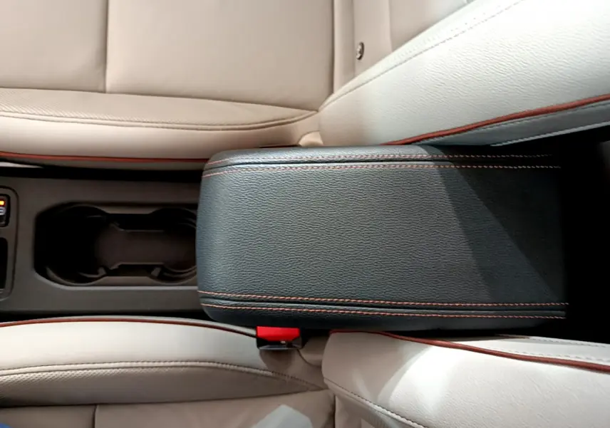 Vue rapprochée de l'accoudoir central noir avec surpiqûres orange et sièges cuir beige de la Renault Clio Initiale Paris E-TECH 2021.