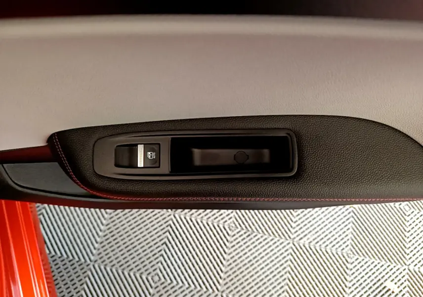 Gros plan sur la poignée intérieure côté gauche de la porte orange d'une Renault Clio Initiale Paris E-TECH 140 2021.