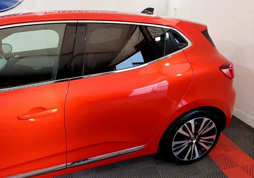 Vue latérale côté gauche d'une Renault Clio Initiale Paris orange avec jantes alliage et vitres teintées