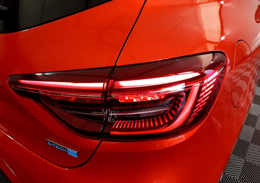 Feu arrière droit allumé sur Renault Clio Initiale Paris E-TECH 140 orange, vue rapprochée du côté arrière droit.
