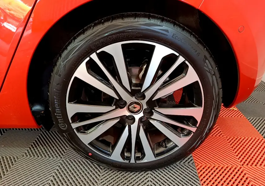 Gros plan sur la roue avant droite de la Renault Clio Initiale Paris orange avec jante alliage bicolore.