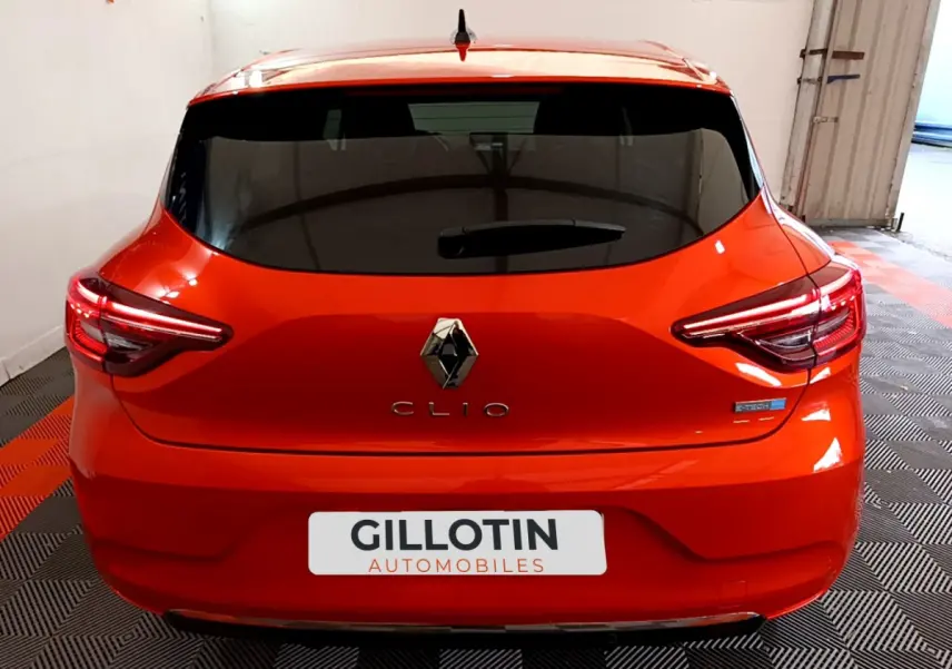 Vue arrière d'une Renault Clio Initiale Paris E-TECH 140 orange vif avec feux LED et logo distinctif Renault.