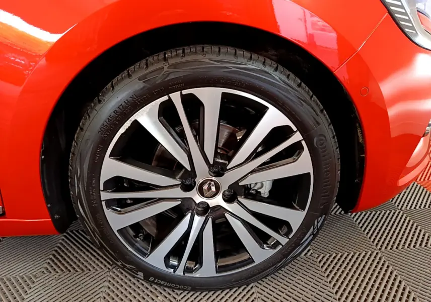 Gros plan sur la roue avant gauche orange d'une Renault Clio Initiale Paris 2021 avec jante alliage noire et argentée.