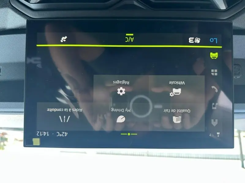 Écran tactile central du tableau de bord du Dacia Duster 2025, affichant les réglages de conduite et climatisation.