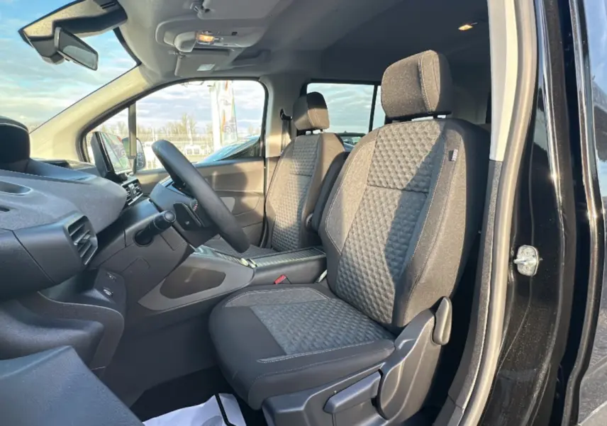 Vue intérieure côté conducteur du Peugeot Rifter 2025 noir perla nera, montrant les sièges tissu et le volant multifonctions cuir.