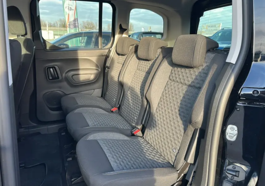 Vue latérale droite des sièges arrière en tissu gris du Peugeot Rifter Noir Perla Nera avec porte ouverte.