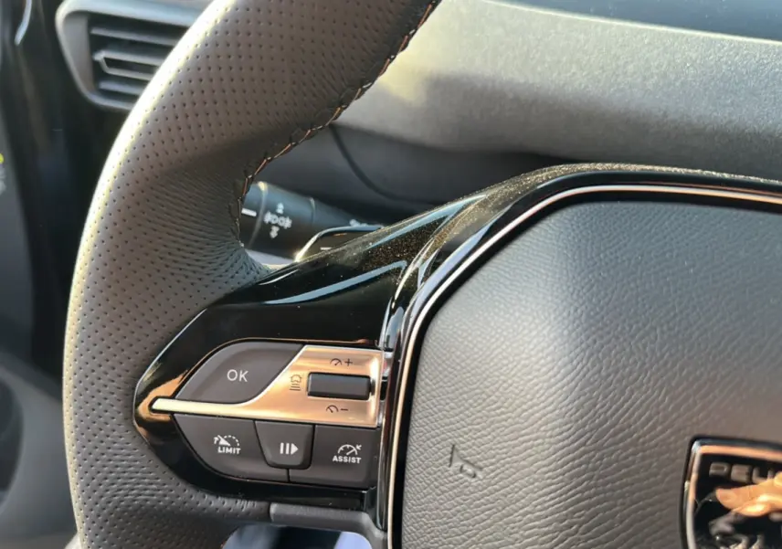 Gros plan sur le volant cuir perforé du Peugeot Rifter 2025 avec commandes multifonctions et finition noire brillante.