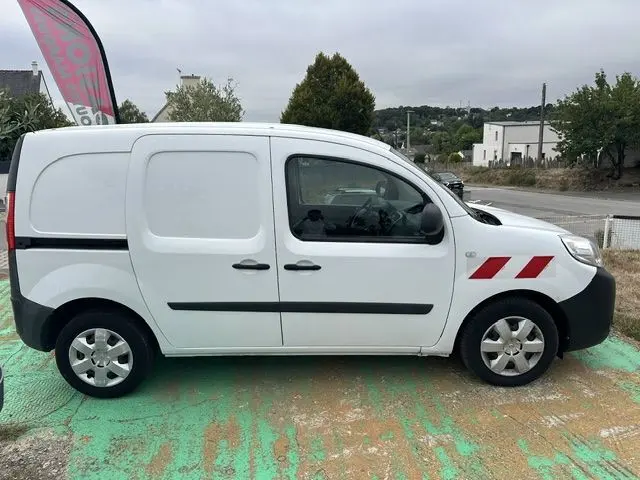 Profil droit d'un Renault Kangoo blanc de 2020 avec marquages rouges sur l'aile avant, stationné en extérieur.