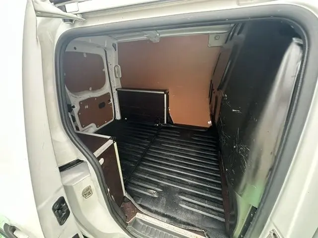 Vue intérieure de la partie arrière du Renault Kangoo blanc 2020, montrant l’espace de chargement vide avec revêtement noir.