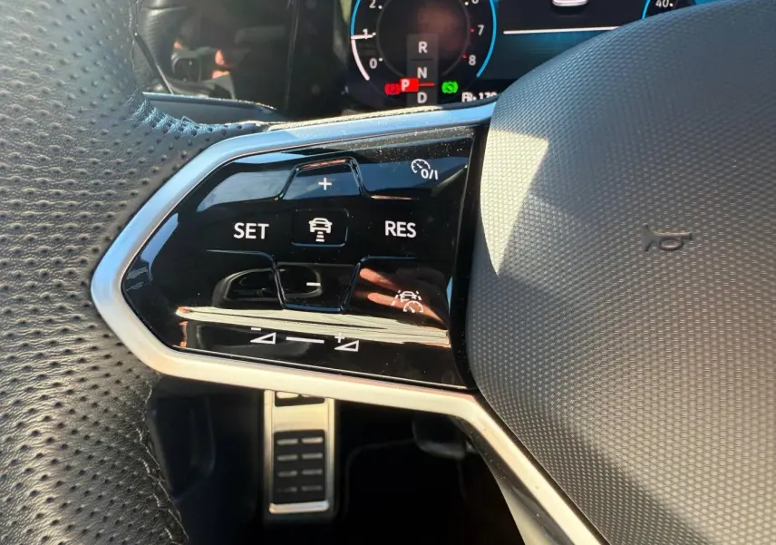 Gros plan sur la partie gauche du volant cuir perforé de la Volkswagen Golf 2024 avec commandes de régulateur de vitesse.