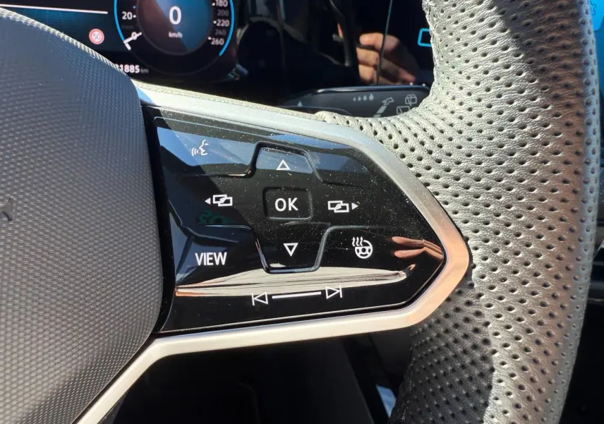 Gros plan sur les commandes noires du volant cuir perforé de la Volkswagen Golf 1.5 eTSI R-Line 2024.