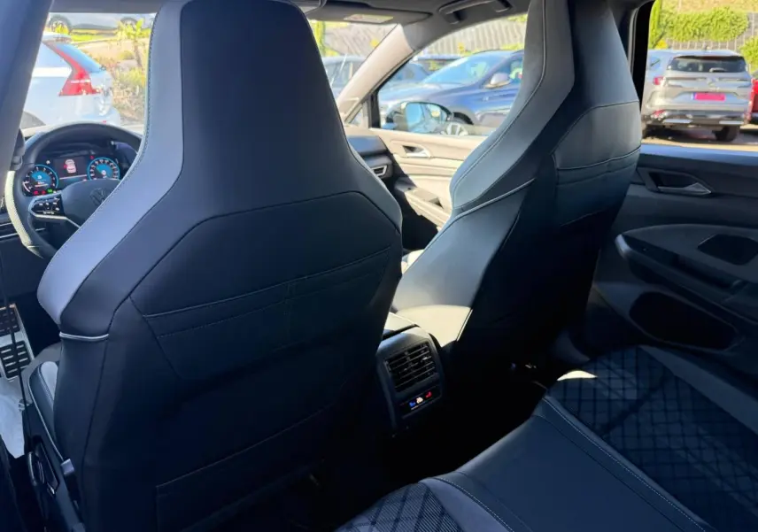 Vue intérieure arrière de la Volkswagen Golf 1.5 eTSI R-Line 2024 avec sièges sport noirs et console centrale avec aérateurs.