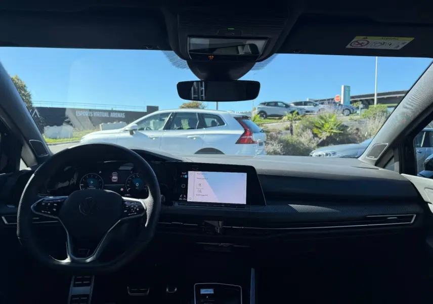 Vue intérieure avant de la Volkswagen Golf noire, avec volant multifonction et écran tactile central lumineux.