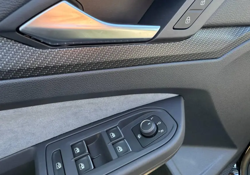 Détail de la porte avant gauche de la Volkswagen Golf 2024 noir Grenadilla, avec commandes des vitres et rétroviseurs.