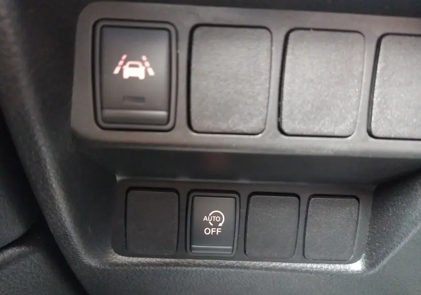 Gros plan sur les boutons de commande du tableau de bord du Nissan Qashqai blanc, avec activation du régulateur automatique.