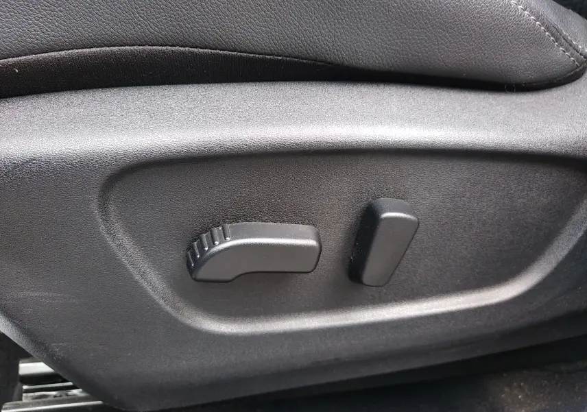 Détail des commandes de réglage électrique du siège conducteur noir dans un Nissan Qashqai blanc 2018.