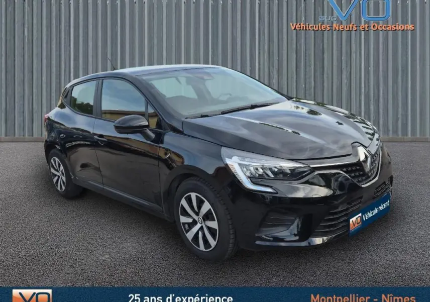 Renault Clio V TCe 90 Equilibre noire vue en 3/4 avant droit sur sol gris devant un mur métallique.