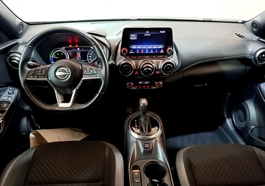 Intérieur noir du Nissan Juke Hybrid 2023 vu de face, avec volant cuir, écran tactile central et levier de boîte auto.