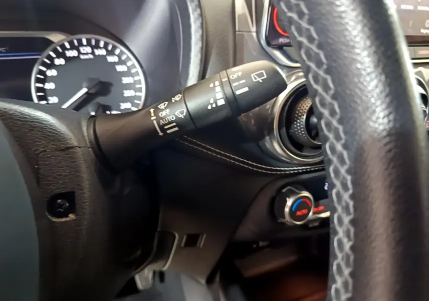 Gros plan sur la commande d'essuie-glace et le volant en cuir du Nissan Juke Hybrid 143 Business+ 2023, intérieur noir.