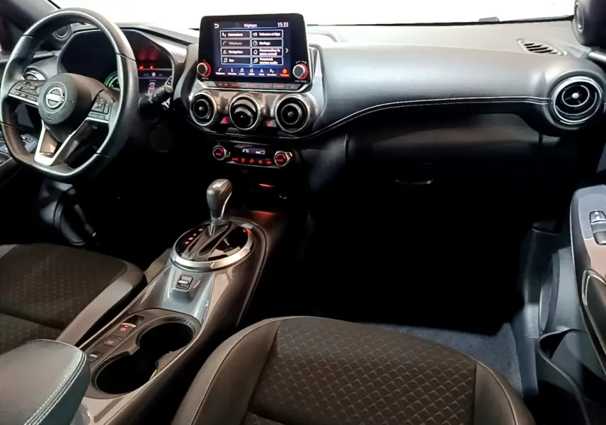 Intérieur du Nissan Juke Hybrid 143 Business+ 2023, vue côté conducteur avec tableau de bord et écran tactile central.