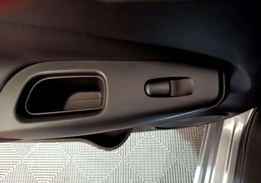 Poignée intérieure et commande de verrouillage côté gauche de la porte d’un Nissan Juke Hybrid gris foncé 2023.