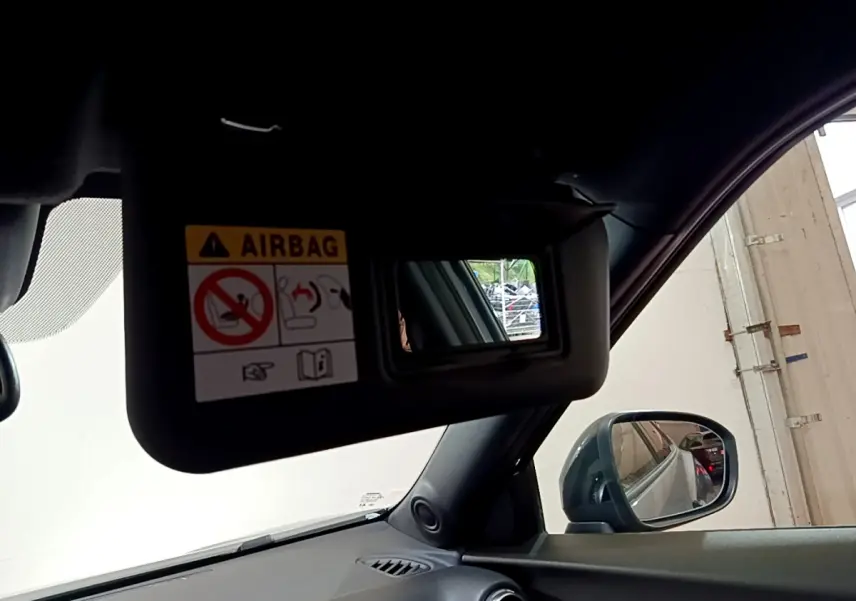 Détail du pare-soleil côté conducteur avec miroir et avertissement airbag, intérieur noir du Nissan Juke Hybrid 2023.