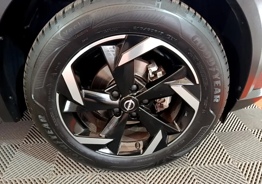 Gros plan sur la jante noire et argentée du Nissan Juke Hybrid 143 Business+ gris foncé, pneu Goodyear visible.