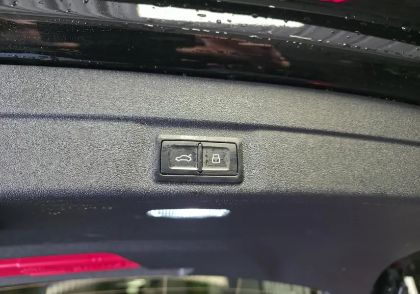Gros plan sur les boutons d'ouverture et de verrouillage du hayon électrique d'une Audi A5 Avant noir 2025.