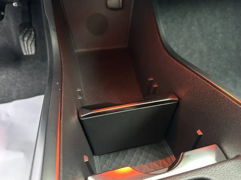 Vue rapprochée de l'accoudoir central avant noir avec rangement, intérieur du Renault Scenic E-Tech rouge 2025.