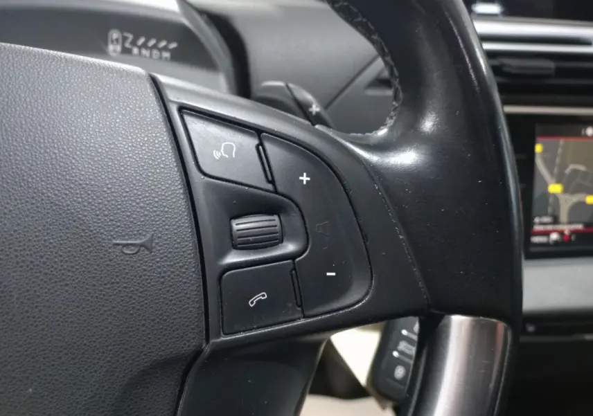Gros plan sur les commandes gauche du volant noir du Citroën Grand C4 Spacetourer avec écran tactile de navigation visible.