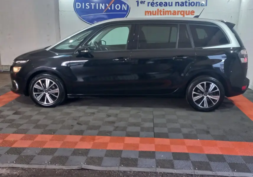 Vue de profil côté gauche d'un Citroën Grand C4 Spacetourer noir stationné en intérieur sur sol à damiers.