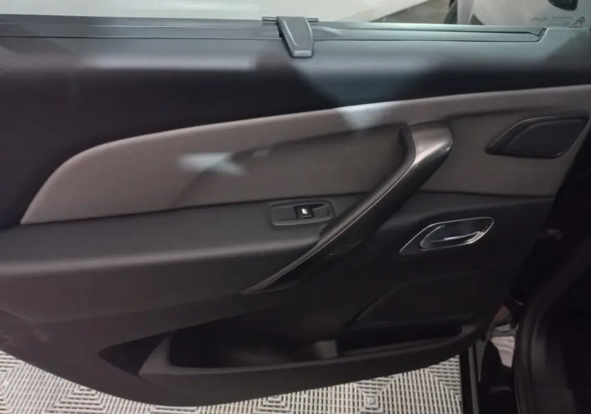 Vue intérieure côté gauche de la porte arrière noire du Citroën Grand C4 Spacetourer avec poignée argentée et bouton de verrouillage.