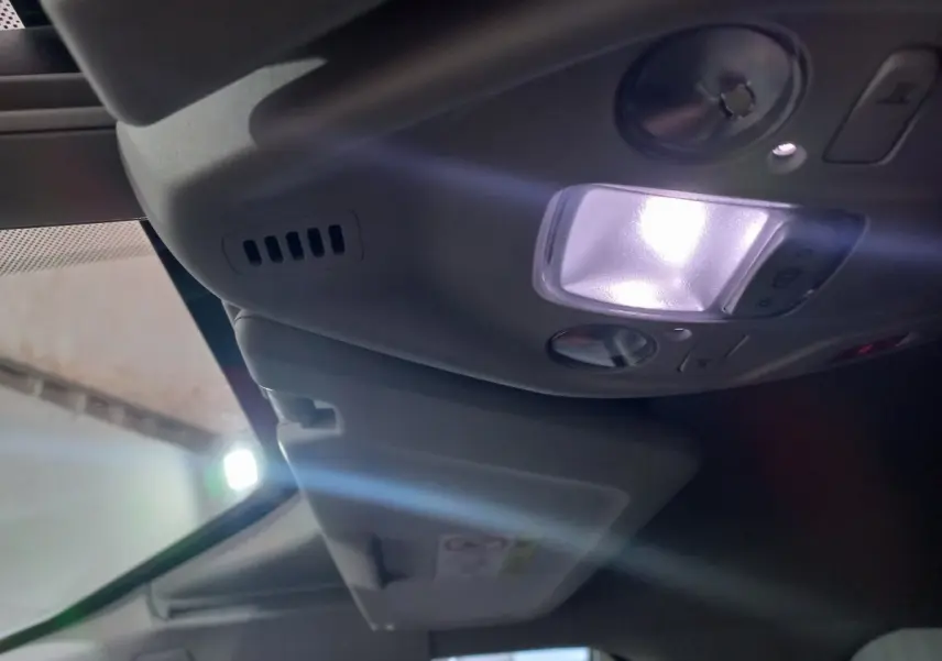 Vue intérieure en plongée sur le plafonnier avec lumière allumée et pare-soleil baissé du Citroën Grand C4 Spacetourer noir.