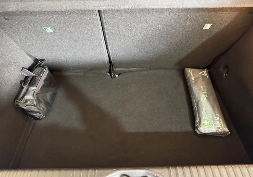 Vue intérieure du coffre noir de la Renault Clio Business TCe 100 GPL avec trousse de secours et kit de sécurité.