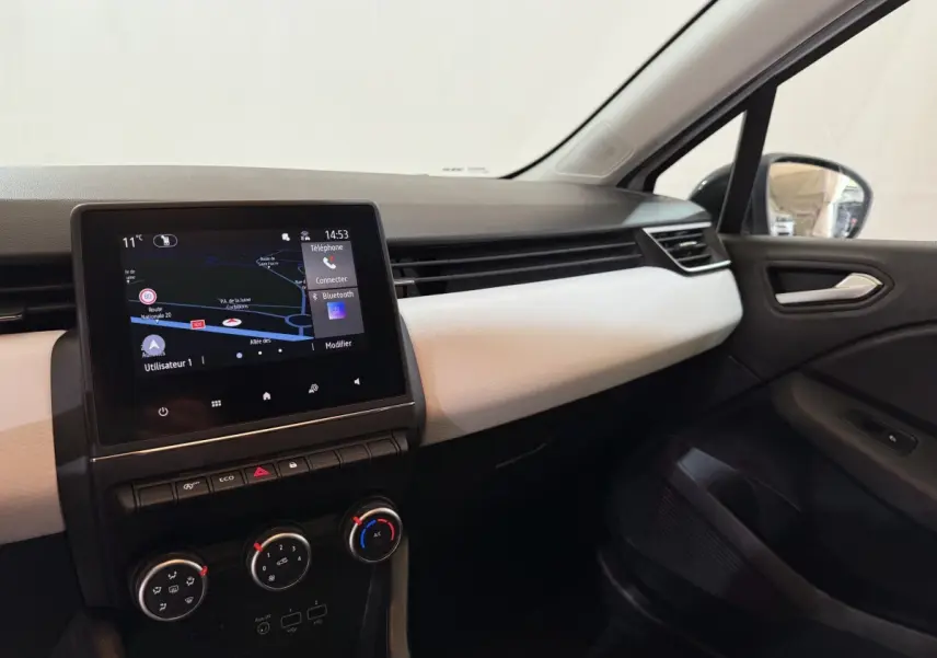 Vue intérieure côté passager de la Renault Clio Business blanche, avec écran tactile de navigation et tableau de bord clair.